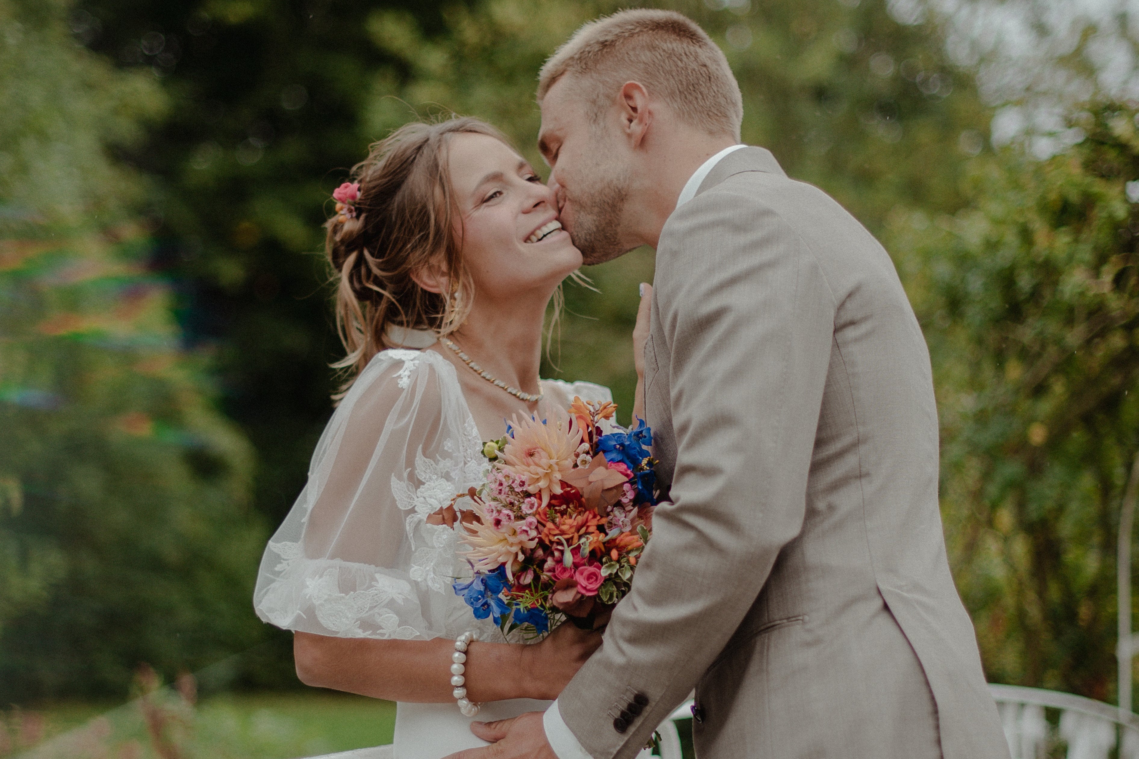 Couple de mariés avec bouquet de mariée coloré de pêche, rose, terracotta et bleu - Mariage dans le Perche - Domaine de Meaucé