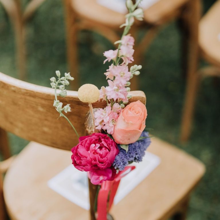 Fleurs colorées en bouquet attachées à une chaise en bois.
