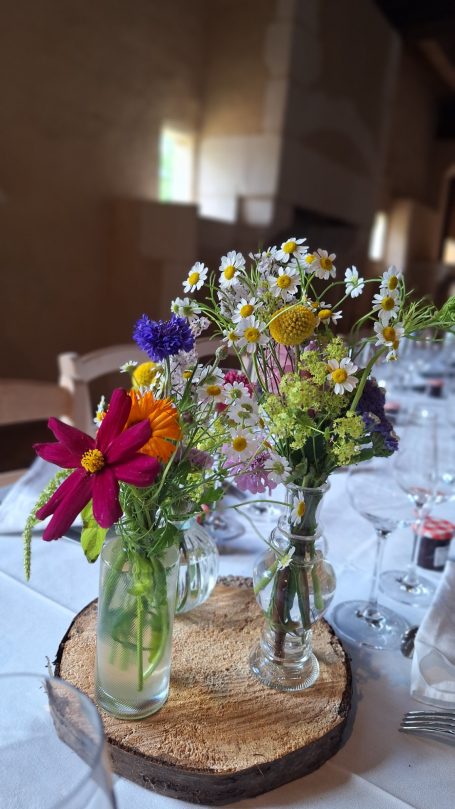 Bouquets de fleurs colorées dans des vases sur une table en bois.