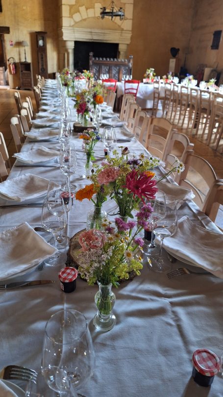 Table dressée avec des fleurs colorées, nappes blanches et vaisselle élégante.