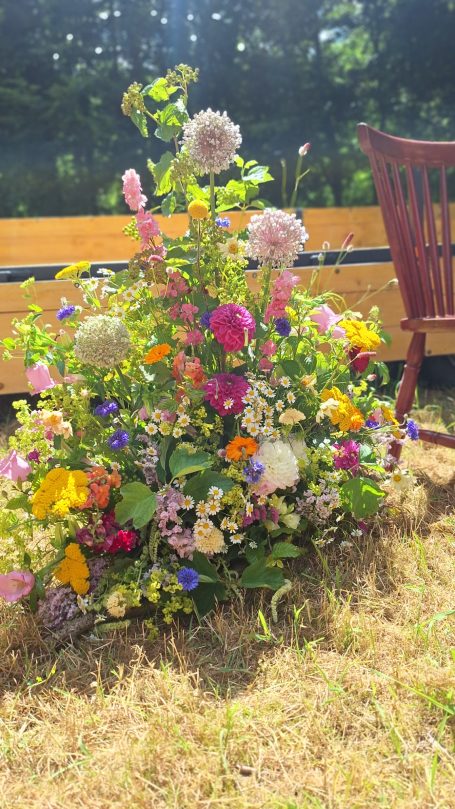 Un bouquet coloré de fleurs variées devant une chaise en bois.