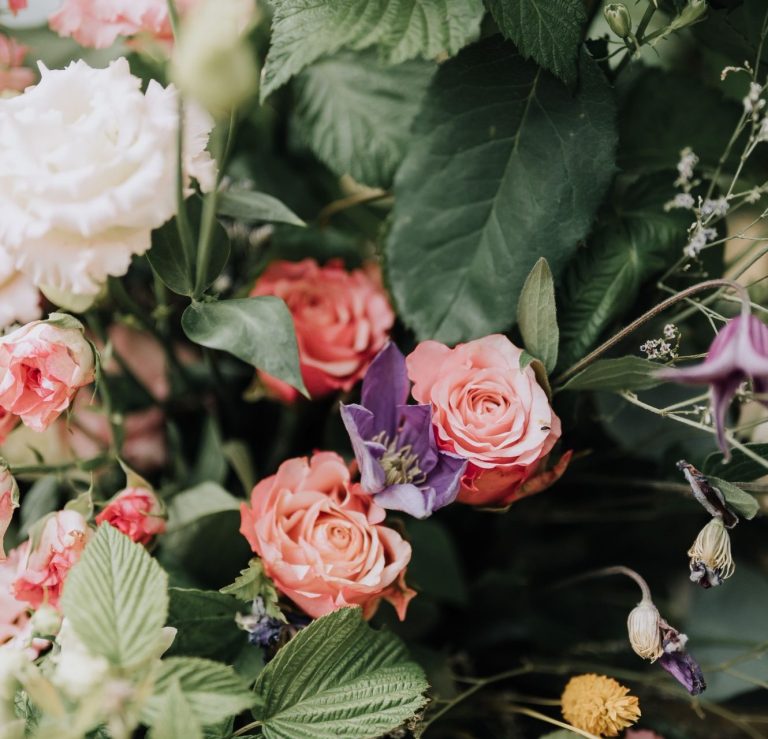 Bouquet de fleurs variées avec des roses et des feuillages luxuriants.