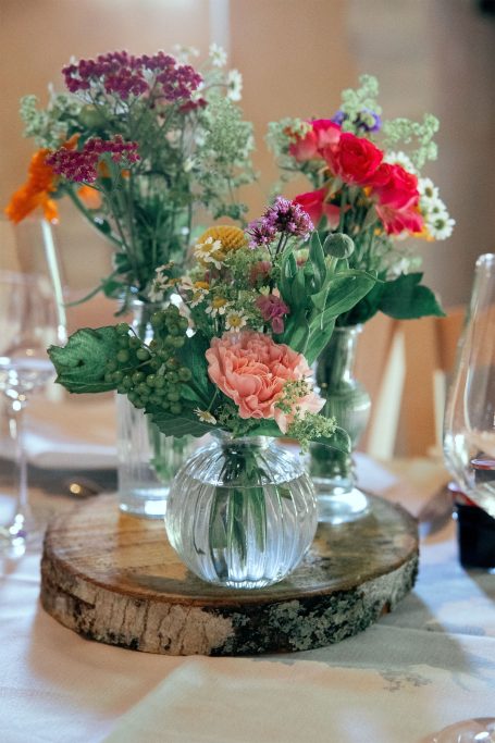 Bouquet de fleurs colorées dans des vases en verre sur une rondelle de bois.