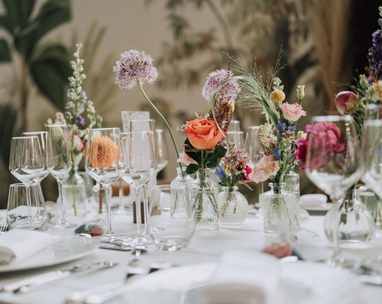 Couple célébrant leur mariage sous un arbre, entourés d'invités heureux lançant des pétales.