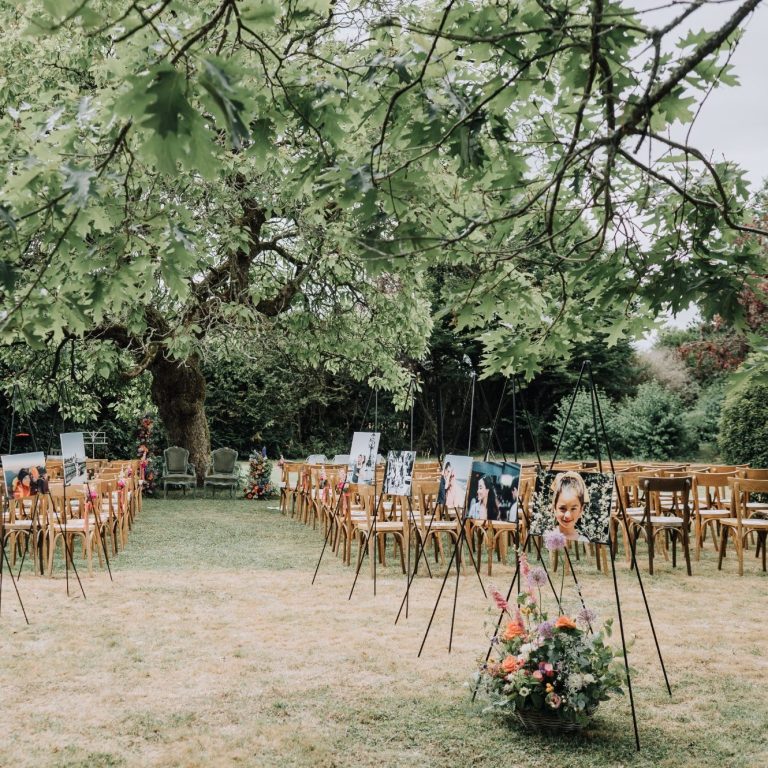 Chairs disposées dans un jardin pour une cérémonie, entourées de fleurs et d'arbres.