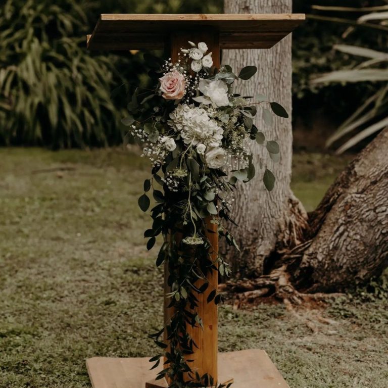 Pupitre en bois décoré de fleurs et feuillage, installé en plein air.