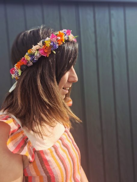 Jeune femme en profil avec une couronne de fleurs, portant un top rayé.