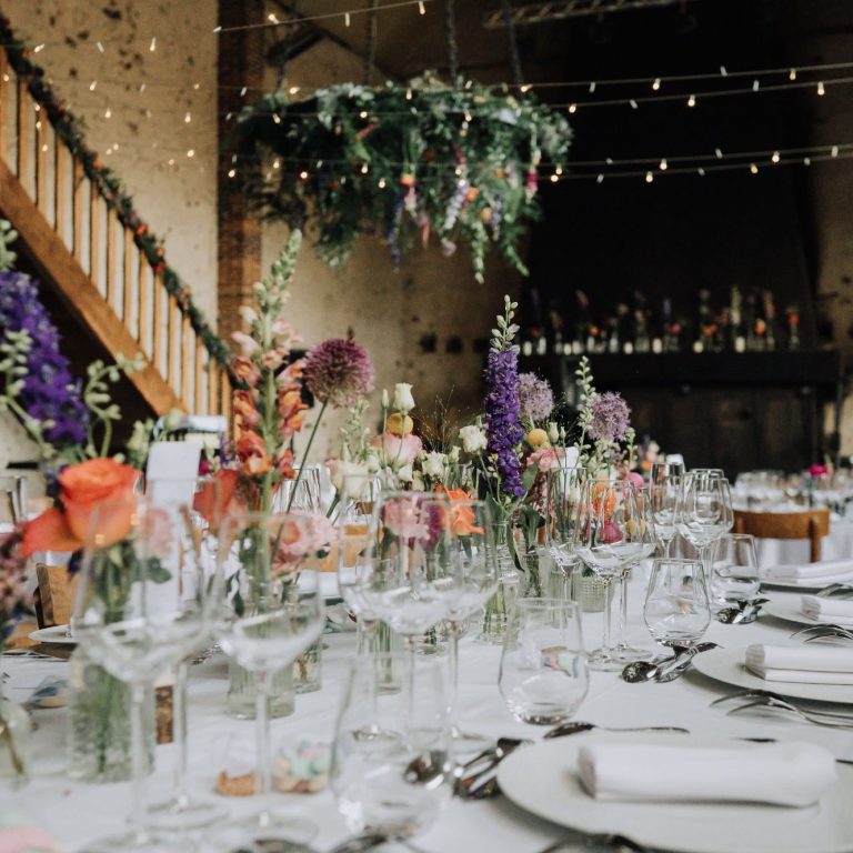 Table décor for a wedding, adorned with vibrant flowers and twinkling lights.