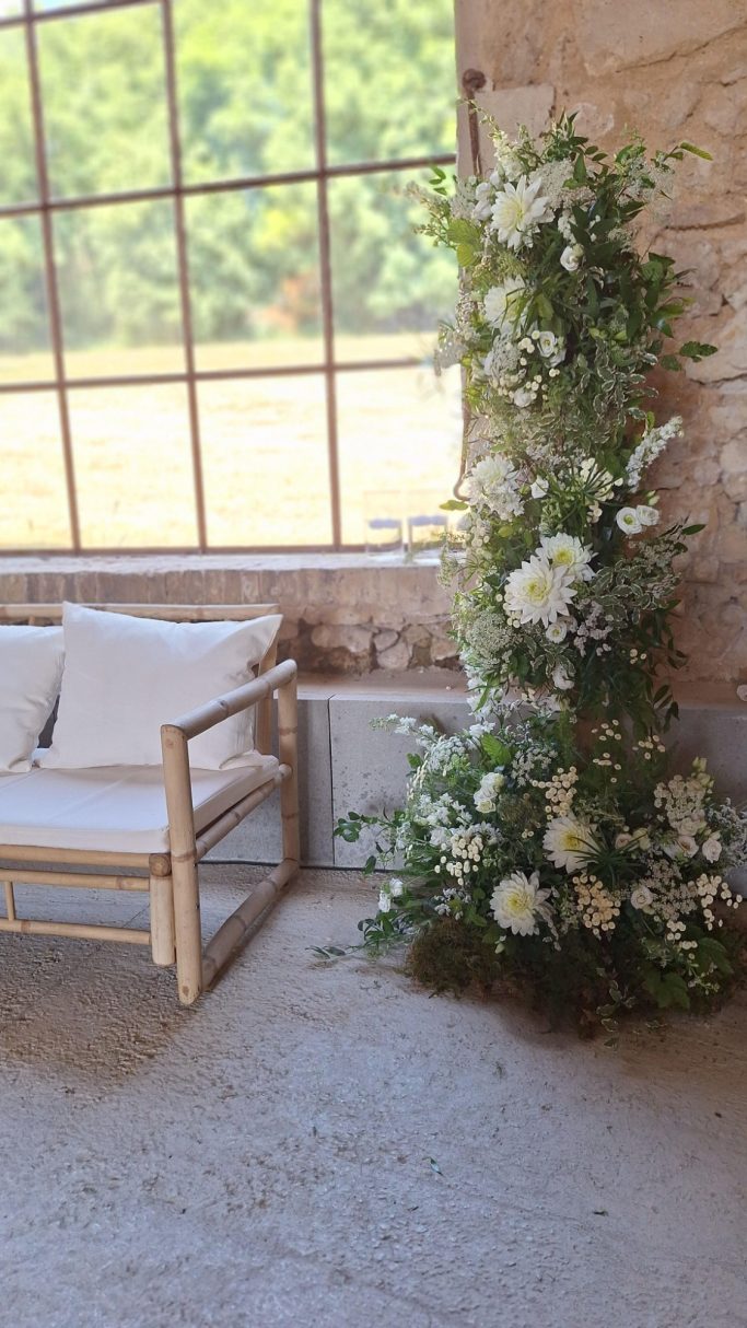 Un coin repos avec un fauteuil en bois et une décoration florale blanche.