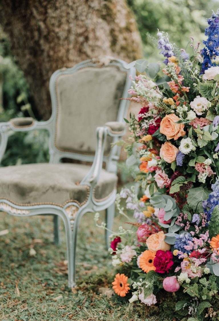 Chaise vintage à côté d'une composition florale colorée dans un cadre naturel.