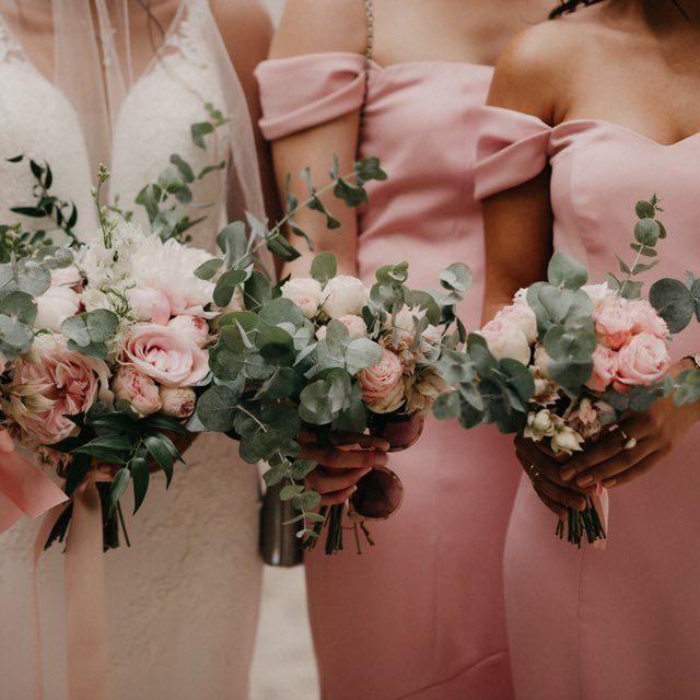 Trois femmes en robes roses tenant des bouquets de fleurs roses et vertes.
