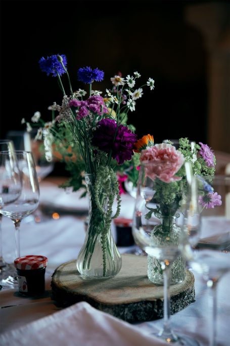 Vases de fleurs mélangeant des couleurs sur une table élégamment dressée.